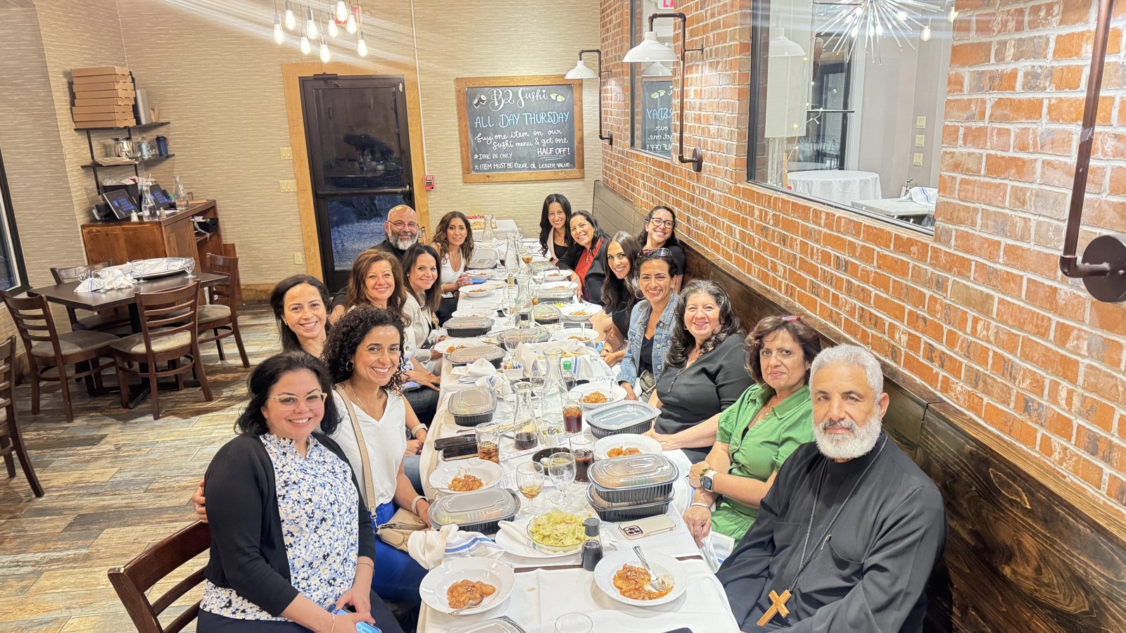 Members of the fellowship gathered around a long table at the women's meeting one-year anniversary dinner